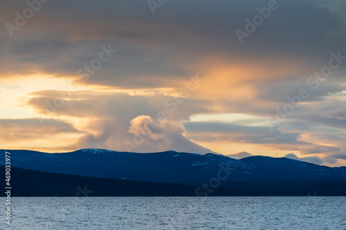 Storm brewing clouds above snow capped mountains in northern Canada with lake and wilderness area. Stunning landscape, background, desktop picture.  © Scalia Media
