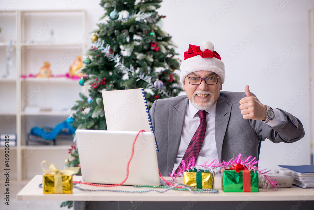 Aged male employee celebrating Christmas at workplace Aged male employee celebrating Christmas at workplace