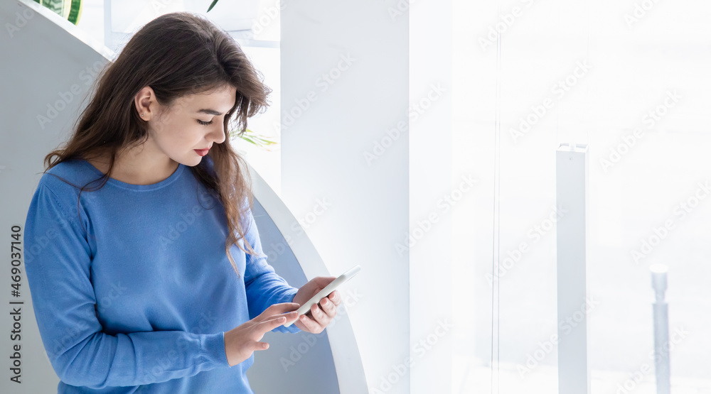 Attractive young woman in a blue sweater uses the phone, copy space. Attractive young woman in a blue sweater uses the phone, copy space.