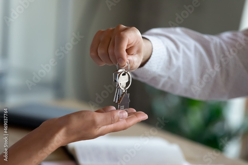 Close up professional realtor giving keys to client, congratulating with purchasing own dwelling after signing contract agreement, professional real estate services, last mortgage payment concept.