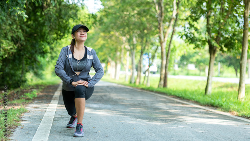 Healthy woman warming up before jogging run and relax stretching her arms and looking away in the road outdoor. Asian runner people workout fitness session, nature park background © freebird7977