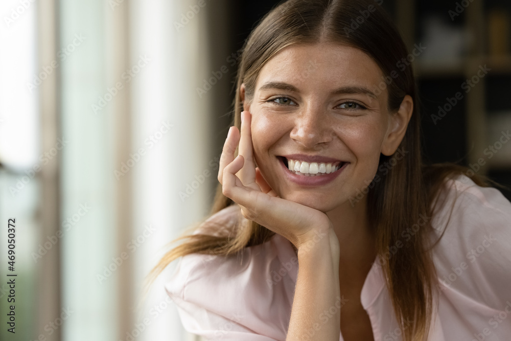 Head shot portrait of beautiful young Caucasian woman with perfect skin and toothy smile posing indoors, copy space for advertising text. Smiling millennial lady enjoying video call conversation. Head shot portrait of beautiful young Caucasian woman with perfect skin and toothy smile posing indoors, copy space for advertising text. Smiling millennial lady enjoying video call conversation.