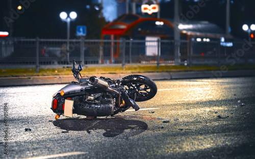 Obraz na płótnie Motorcycle lying on asphalt after an road accident. Moto bike collision at night. Damaged motorcycle lay on asphalt road w salonie