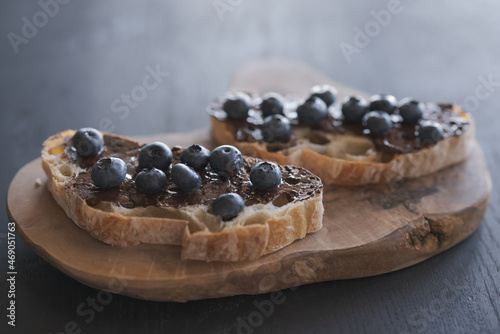 Toasted chiabatta slices with chocolate hazelnut spread with fresh blueberries on olive board