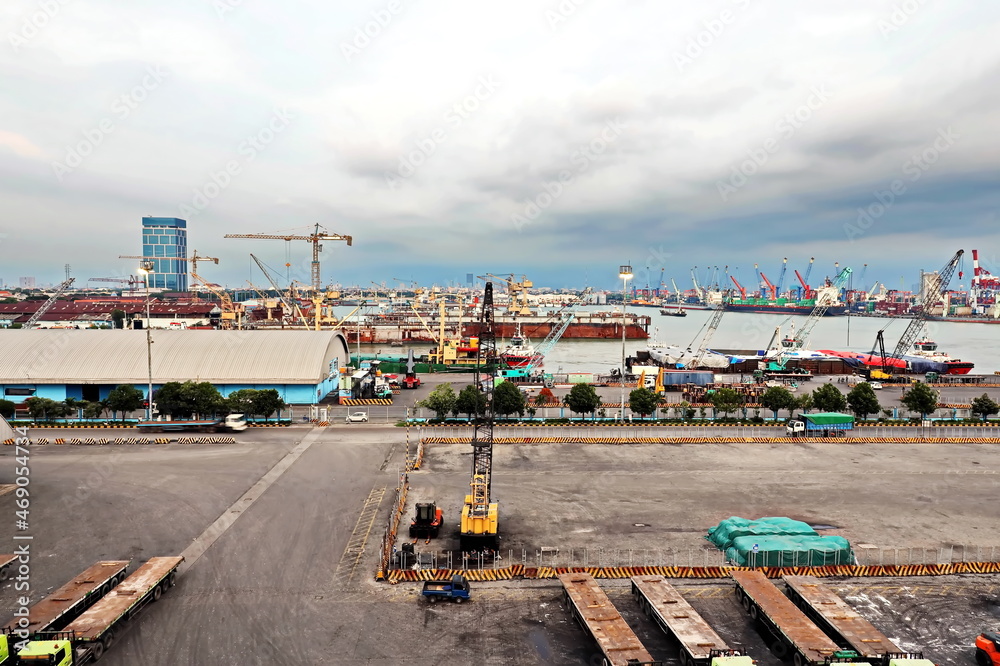 Cargo terminal for unloading steel plates from bulk carrier by ships cranes. View of the pier, cranes and various equipment. Port of Surabaya. Indonesia, January, 2021.