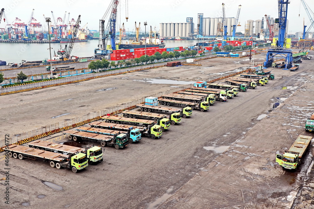 Cargo terminal for unloading steel plates from bulk carrier by ships cranes. View of the pier, cranes and various equipment. Port of Surabaya. Indonesia, January, 2021.