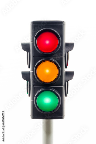 Vertical view of a traffic light showing illuminated red, amber, and green lights.  Concept image illustrating control of the COVID pandemic and confusion.

