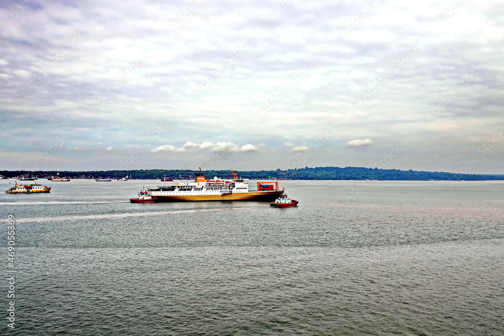 Obraz premium Vessels, passenger ships and tugboats in port under cargo operations and underway. Port of Surabaya, Indonesia, January,2021