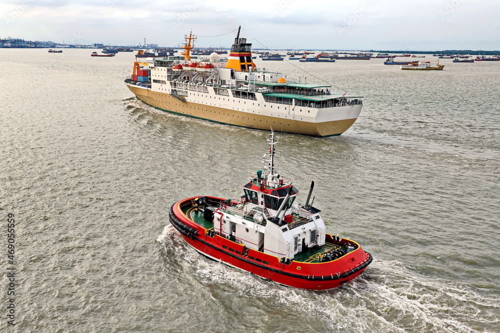 Fototapeta premium Vessels, passenger ships and tugboats in port under cargo operations and underway. Port of Surabaya, Indonesia, January,2021