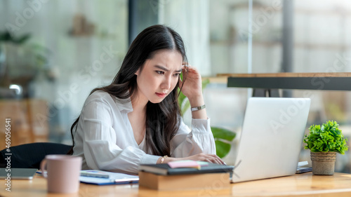 Stressful day. Young Asian businesswoman stressed while working on laptop at office.