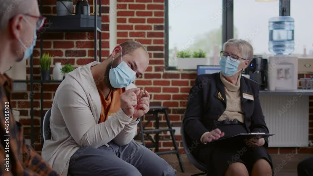 Person with face mask sharing anger management issues with group at aa meeting, asking for help and support from psychologist. Angry man talking about addiction and mental health problems Person with face mask sharing anger management issues with group at aa meeting, asking for help and support from psychologist. Angry man talking about addiction and mental health problems