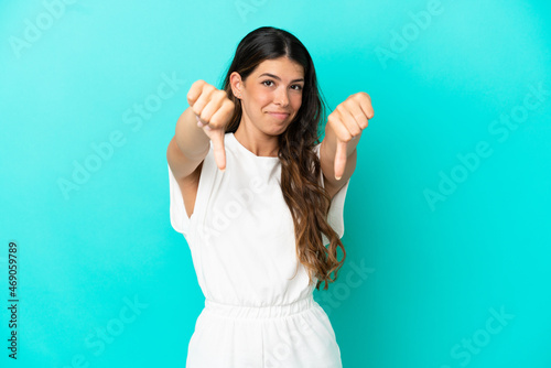 Young caucasian woman isolated on blue background showing thumb down with two hands