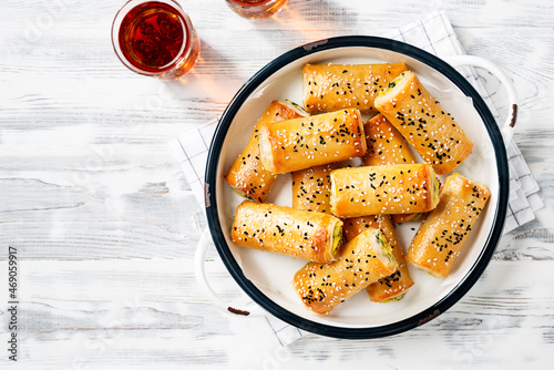 Turkish borek rolls with spinach and cheese. A traditional Turkish pastry rulo borek with black and white sesame seeds. White  wooden background. top view photo