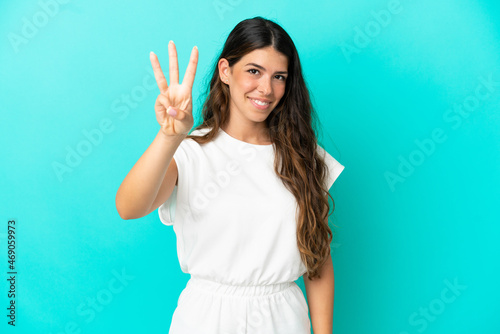 Young caucasian woman isolated on blue background happy and counting three with fingers