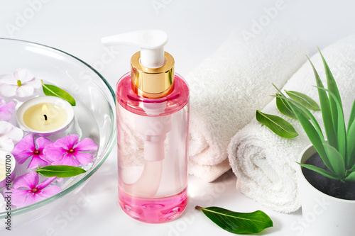 Delicate background, intimate hygiene gel, white towels and a container with pink flowers for aromatherapy. photo