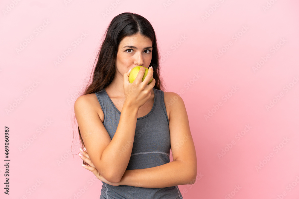 Young caucasian woman isolated on pink background eating an apple Young caucasian woman isolated on pink background eating an apple