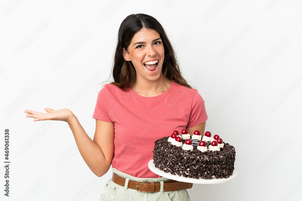 Young caucasian woman holding birthday cake isolated on white background with shocked facial expression Young caucasian woman holding birthday cake isolated on white background with shocked facial expression