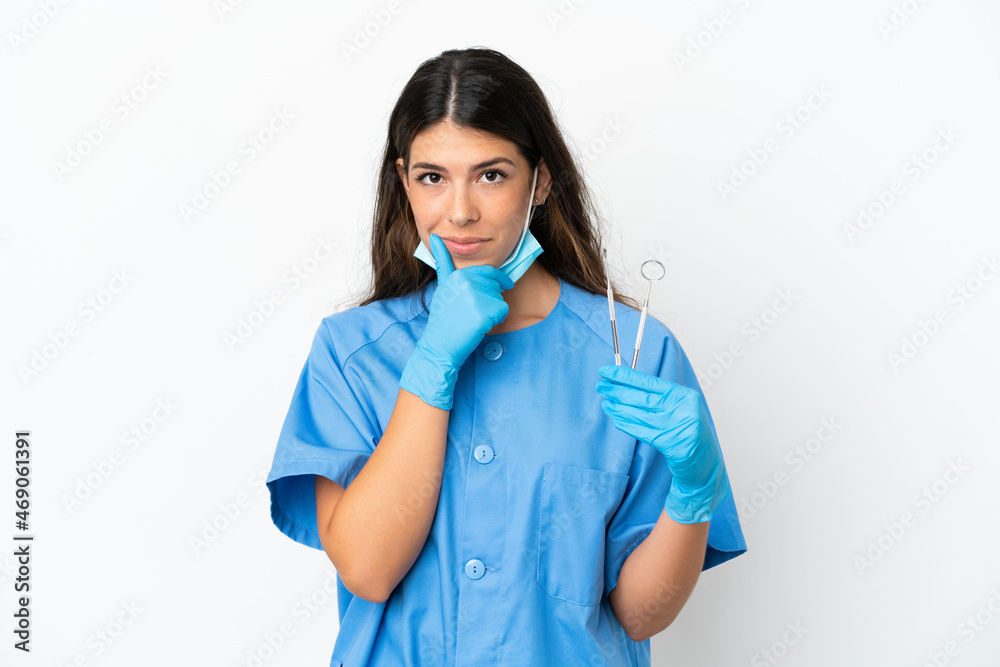 Dentist woman holding tools over isolated white background thinking