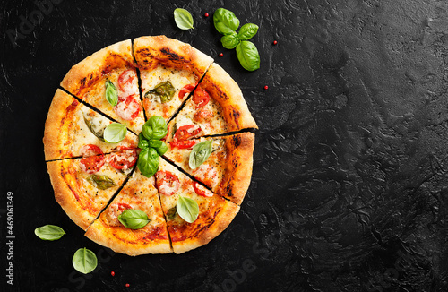 Fresh Homemade Italian Pizza Margherita with mozzarella cheese,cherry tomatoes and fresh basil leaves. Black stone background, top view 