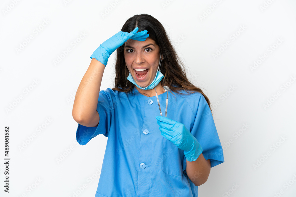 Dentist woman holding tools over isolated white background doing surprise gesture while looking to the side Dentist woman holding tools over isolated white background doing surprise gesture while looking to the side