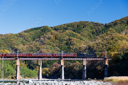 長瀞秩父鉄道、青空と山を背景に荒川橋梁を渡る蒸気機関車と客車