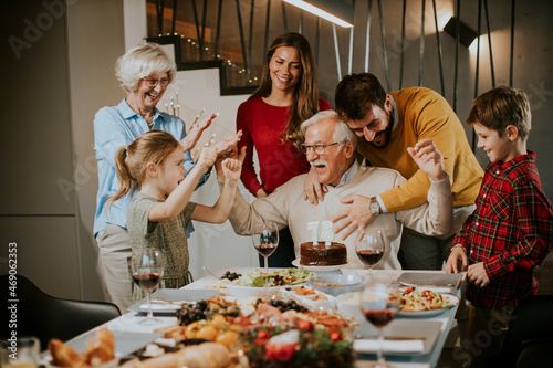 Family celebrating grandfather birthday with cake and candles at home