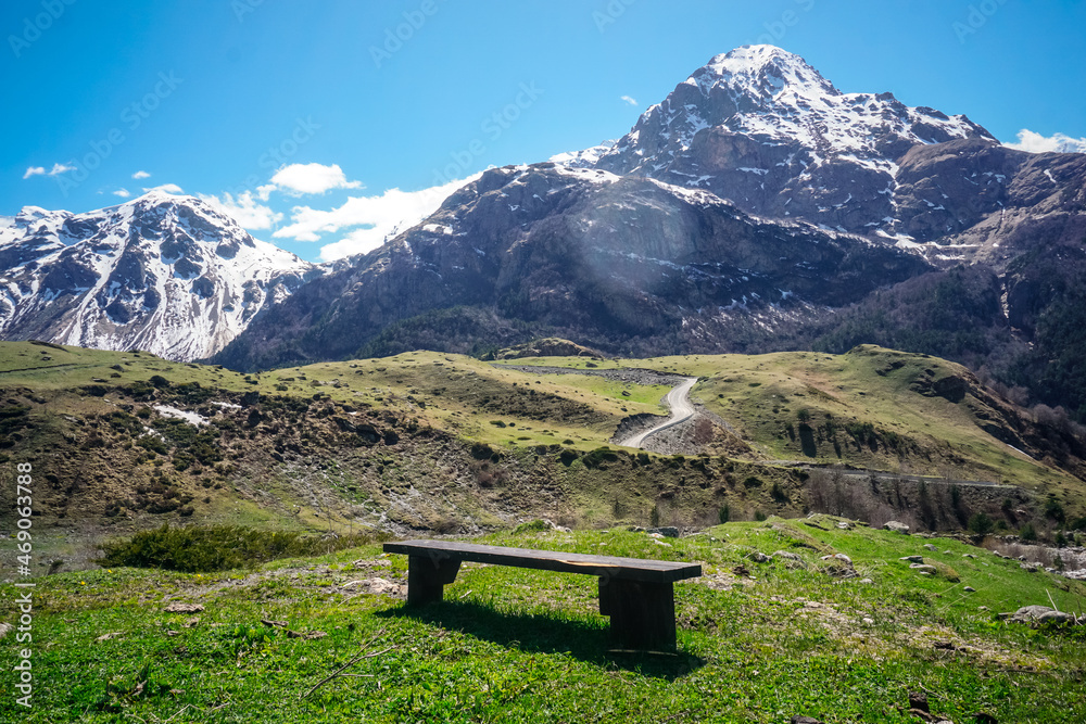 Wooden bench on the lawn overlooking the snow capped mountains