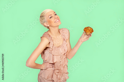 Close-up portrait of beautiful cute gourmet attractive funny cheerful positive crazy girl holding cake, cupcake or muffin isolated on green pastel background.