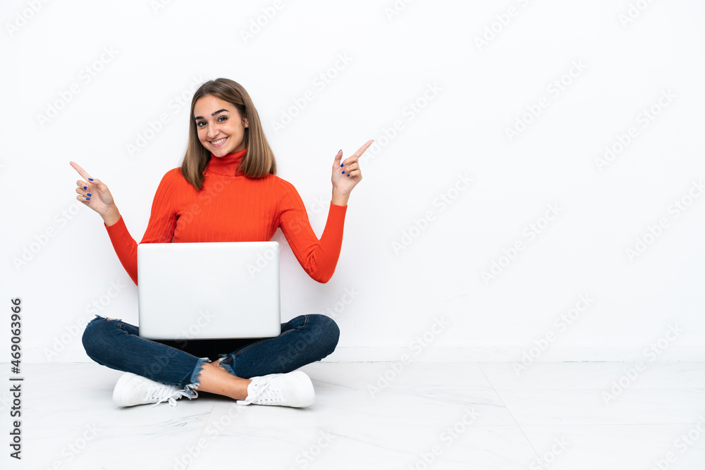 Young caucasian woman sitting on the floor with a laptop pointing finger to the laterals and happy Young caucasian woman sitting on the floor with a laptop pointing finger to the laterals and happy