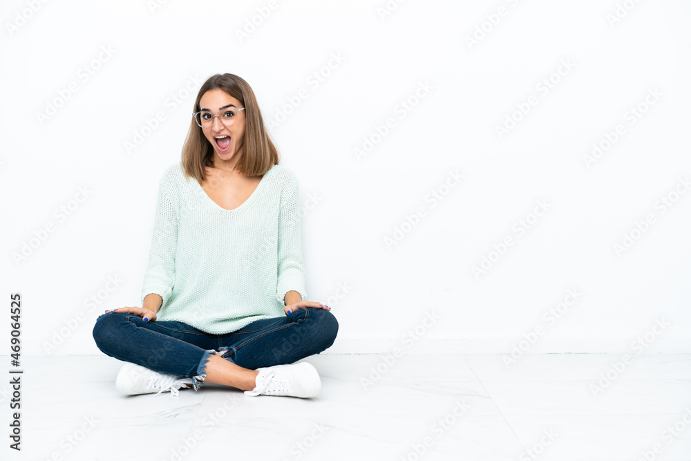 Young caucasian woman sitting on the floor isolated on white background with surprise facial expression Young caucasian woman sitting on the floor isolated on white background with surprise facial expression