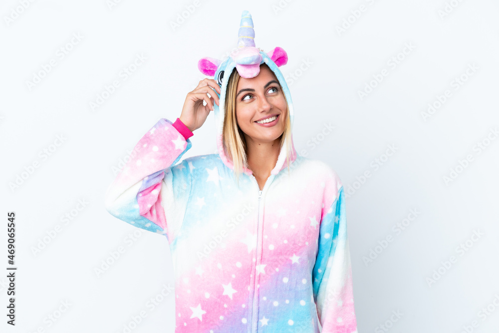 Blonde Uruguayan girl wearing a unicorn pajama isolated on white background having doubts and with confuse face expression Blonde Uruguayan girl wearing a unicorn pajama isolated on white background having doubts and with confuse face expression
