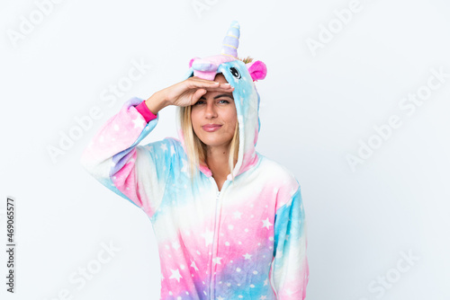 Blonde Uruguayan girl wearing a unicorn pajama isolated on white background looking far away with hand to look something