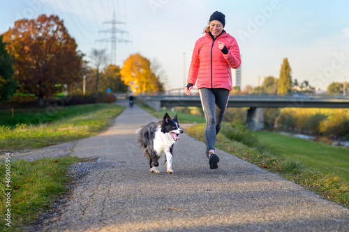 Happy vivacious woman running with her Border Collie
