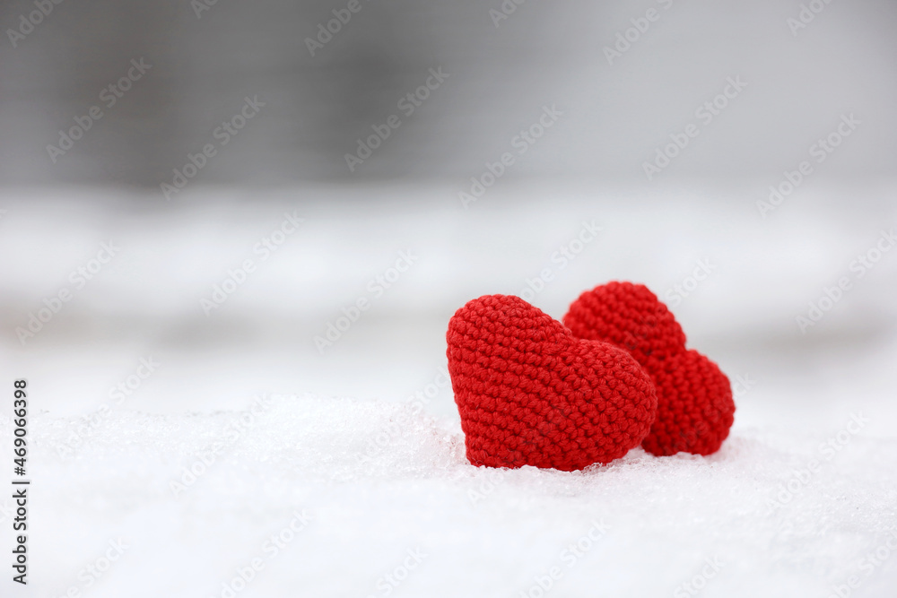 Fototapeta premium Love hearts in the snow in a park. Valentine's card, two red knitted symbols of love, background for romantic event in winter, Christmas celebration