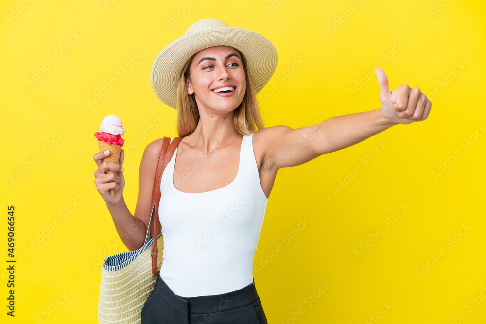 Blonde Uruguayan girl in summertime holding ice cream isolated on yellow background giving a thumbs up gesture Blonde Uruguayan girl in summertime holding ice cream isolated on yellow background giving a thumbs up gesture