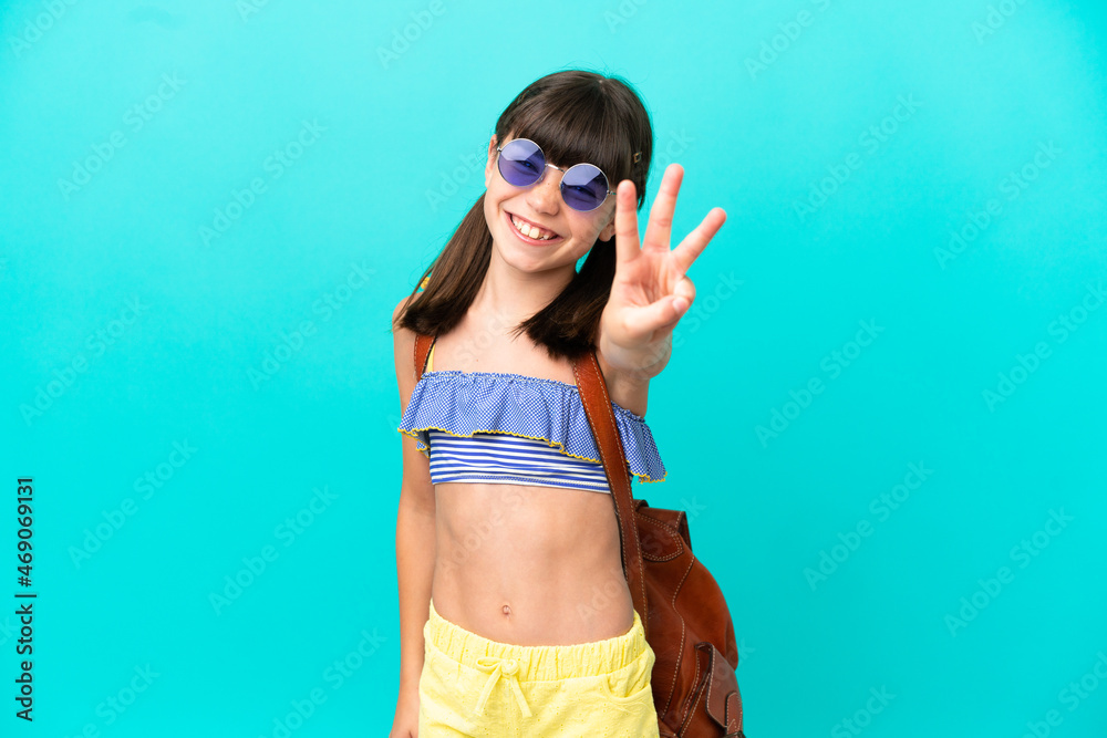 Little caucasian kid going to the beach isolated on blue background happy and counting three with fingers
