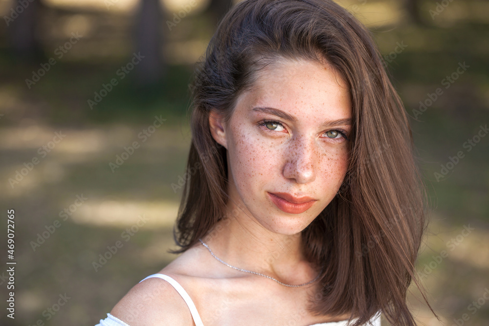 Young beautiful brown-haired girl with freckles on her face Young beautiful brown-haired girl with freckles on her face