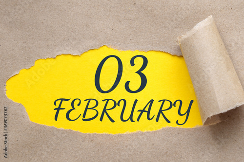 february 03. 03th day of the month, calendar date.Hole in paper with edges torn off. Yellow background is visible through ragged hole.Winter month, day of the year concept photo