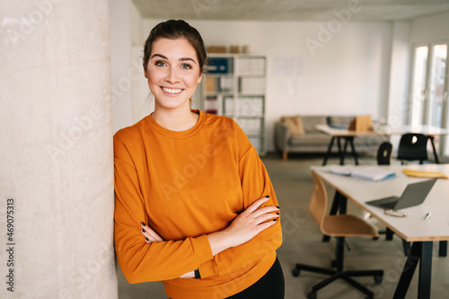 Relaxed confident young businesswoman leaning on a pillar