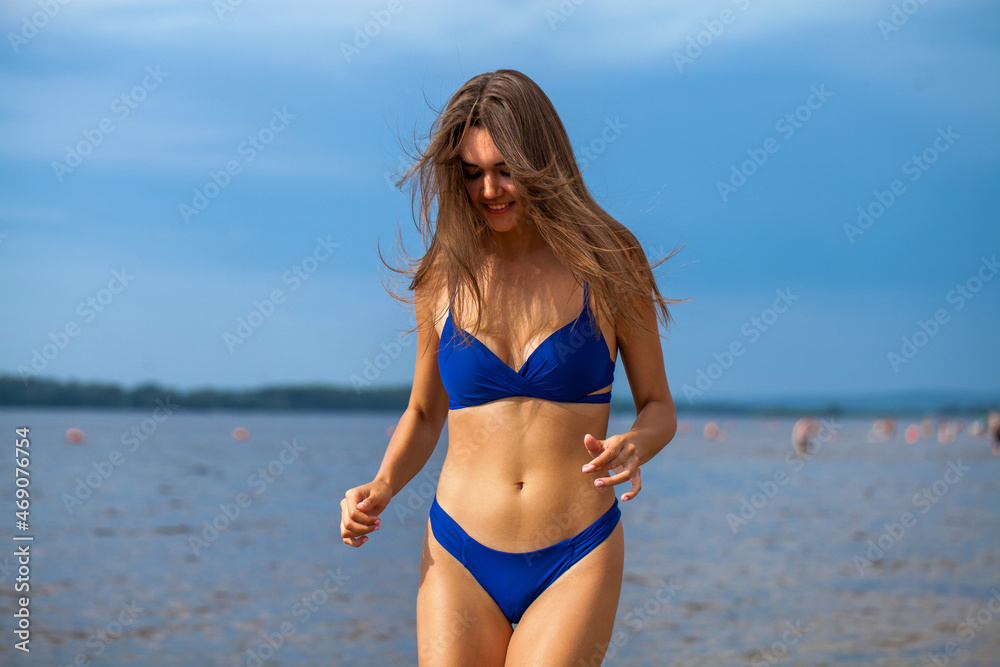 Portrait of a young beautiful brunette woman posing in blue bikini