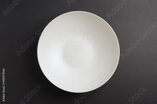 Top down minimalist view of a white bowl on yellow background. White round plate on grey black background	