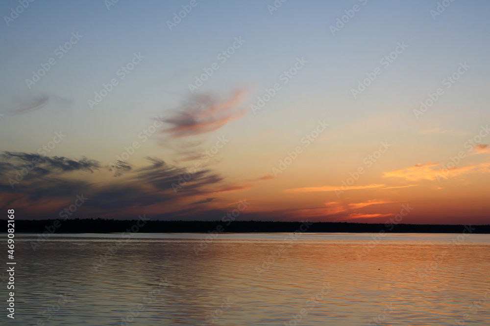 Sunset on Lake Ladoga, blue sky, clouds, forest on the distant shore - view from the ship