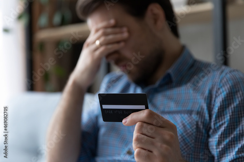 Billede på lærred Depressed unhappy young man holding credit card in hands, feeling stressed having financial problems, dissatisfied with insecure money transfer operation or bank loan debt, bankruptcy concept
