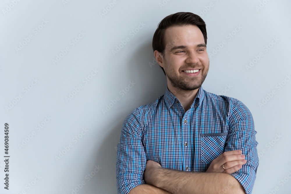 Smiling young man looking in distance, standing with folded arms, posing on white blank studio background. Millennial guy visualizing future, planning weekend, copy space for advertisement text. Smiling young man looking in distance, standing with folded arms, posing on white blank studio background. Millennial guy visualizing future, planning weekend, copy space for advertisement text.