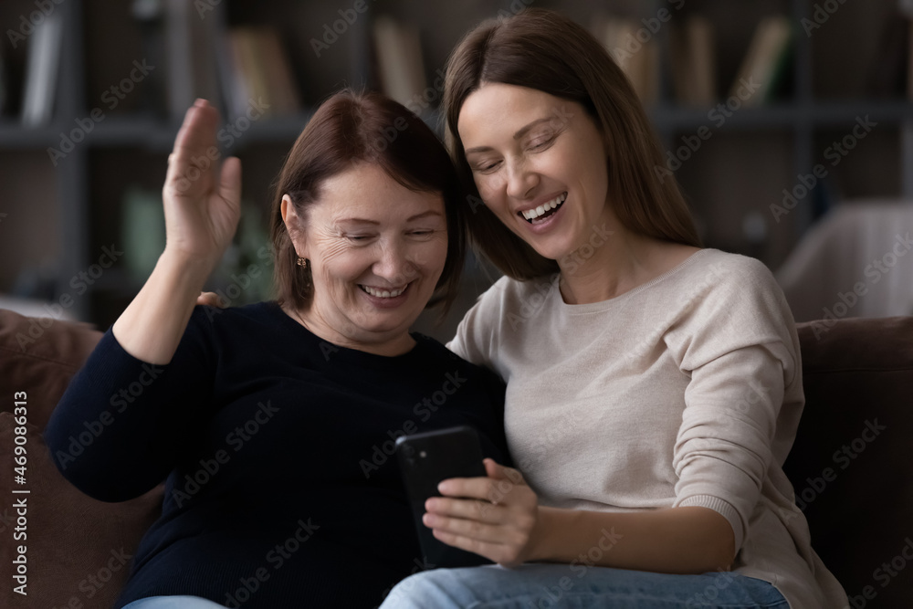 Happy woman with mature mother using smartphone, making video call together, happy senior mom with daughter waving hand at cellphone webcam, family chatting online, enjoying leisure time with device Happy woman with mature mother using smartphone, making video call together, happy senior mom with daughter waving hand at cellphone webcam, family chatting online, enjoying leisure time with device