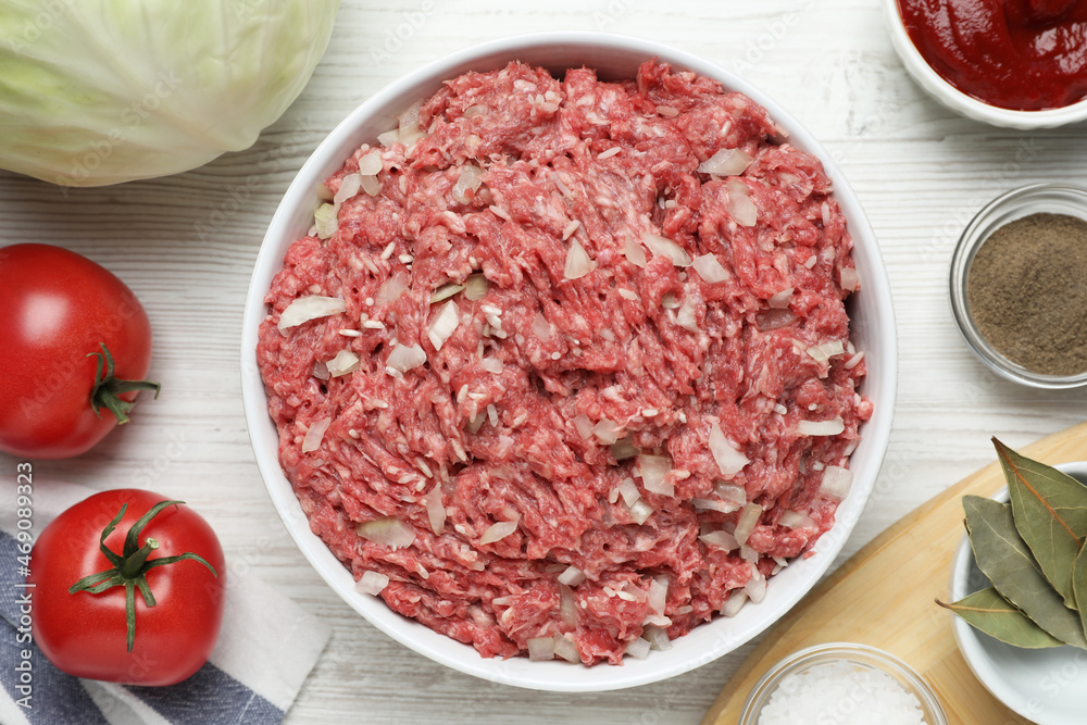 Meat filling in bowl and other ingredients for stuffed cabbage rolls on white wooden table, flat lay Meat filling in bowl and other ingredients for stuffed cabbage rolls on white wooden table, flat lay