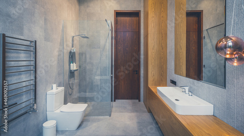 Interior of bathroom in luxury flat. Grey and wooden design. Glass shower.