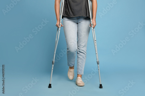 Obraz na płótnie Woman with crutches on light blue background, closeup