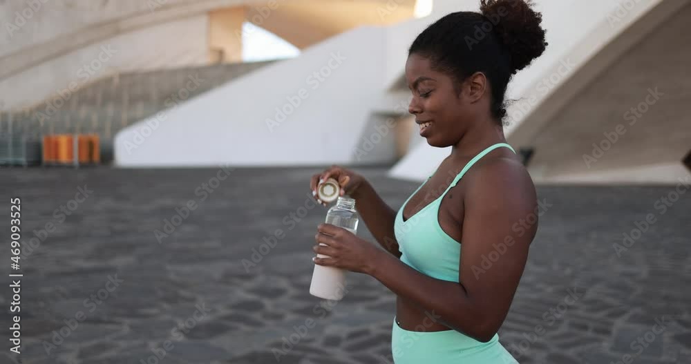 Happy african girl drinking watter after sport workout in the city