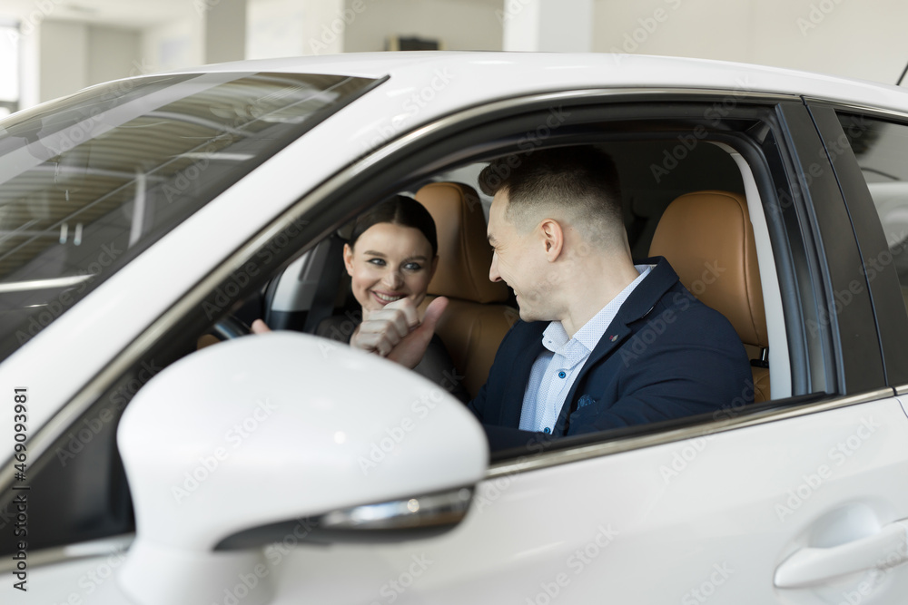 Married couple husband and wife sitting in a car in a car dealership. Test the car before buying. Married couple husband and wife sitting in a car in a car dealership. Test the car before buying.